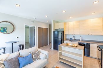 A modern kitchen with a black refrigerator and wooden cabinets.at Rowat Lofts, Des Moines Iowa   